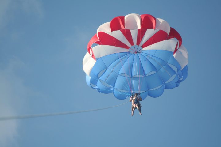 a parachute is flying through the air while holding a blue umbrella